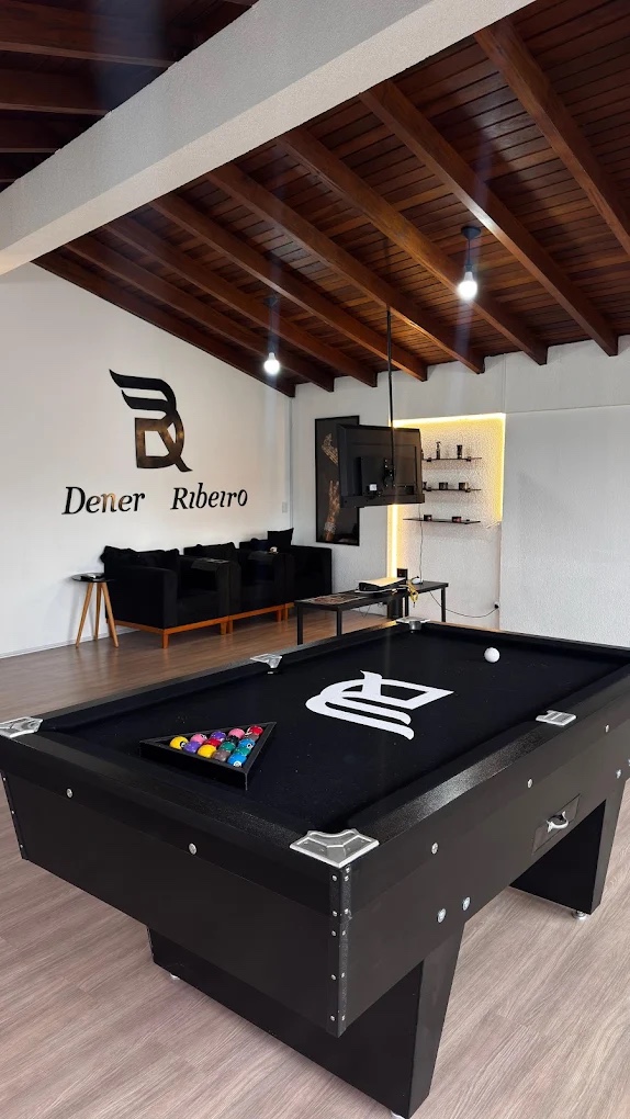 Parede com a marca Dener Ribeiro, sofás e mesa de sinuca